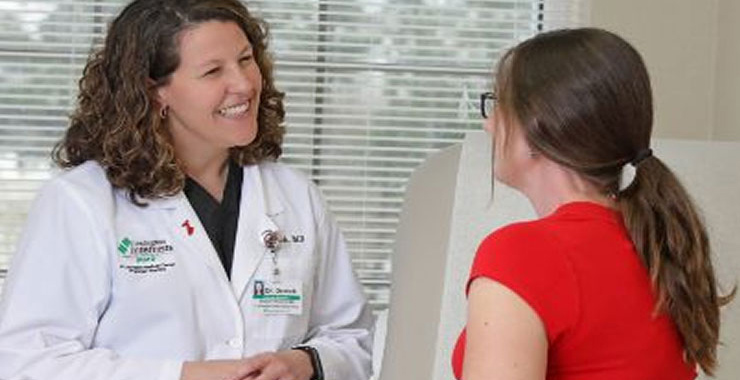 A doctor smiling with a patient in the examination room.