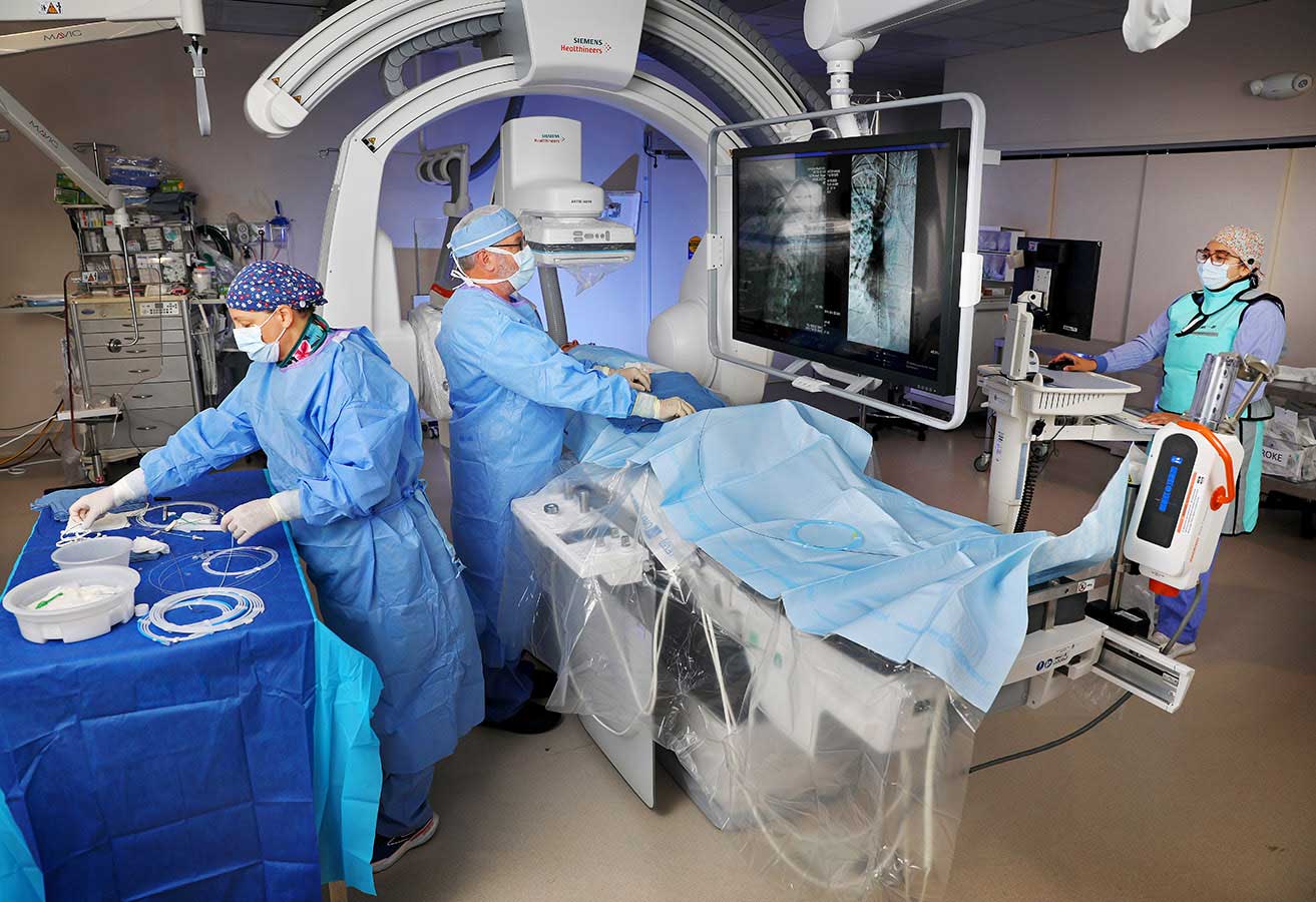 A team of doctors and nurses using imaging equipment on a patient.