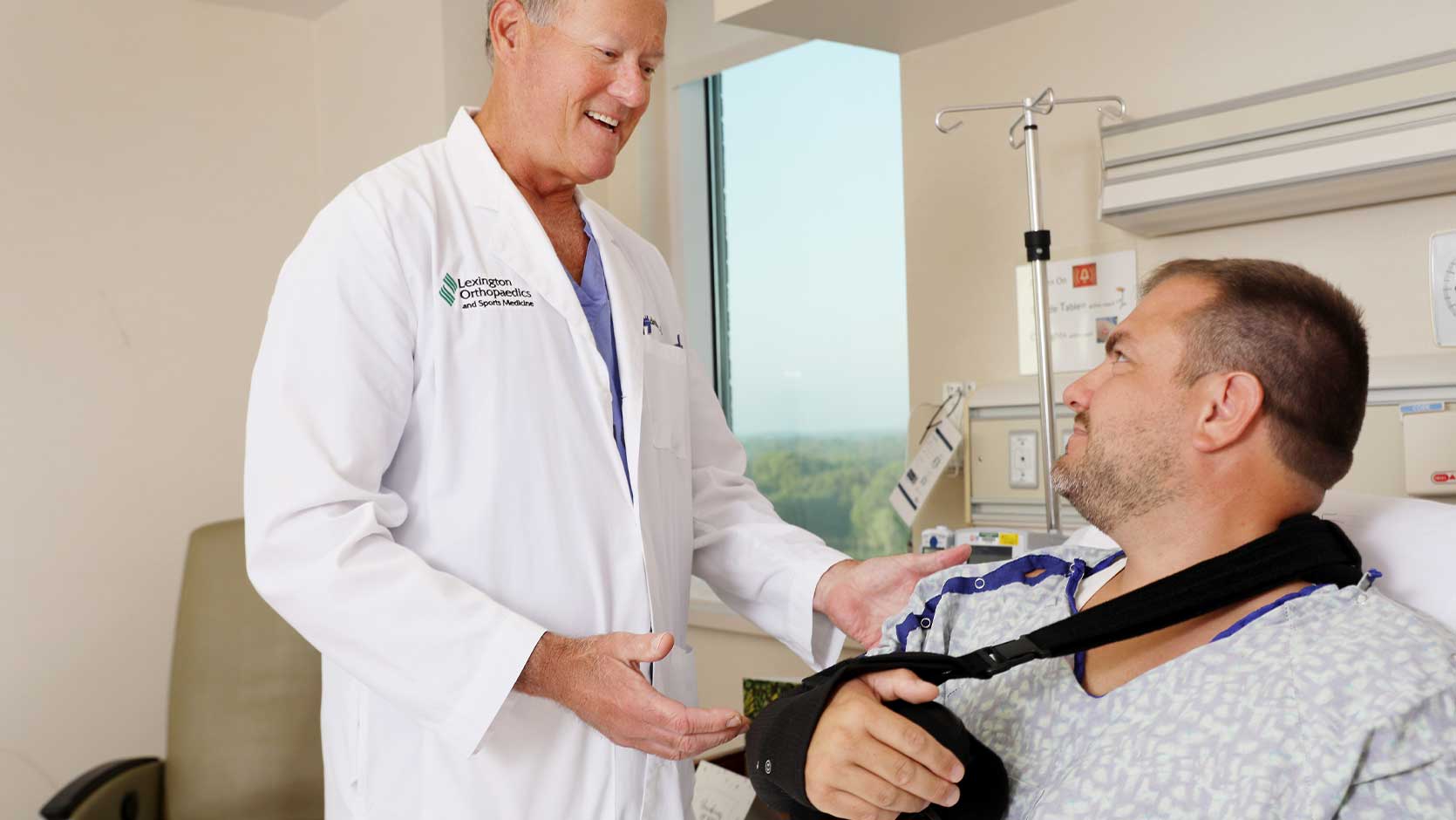 A doctor speaking to a patient wearing an arm sling.