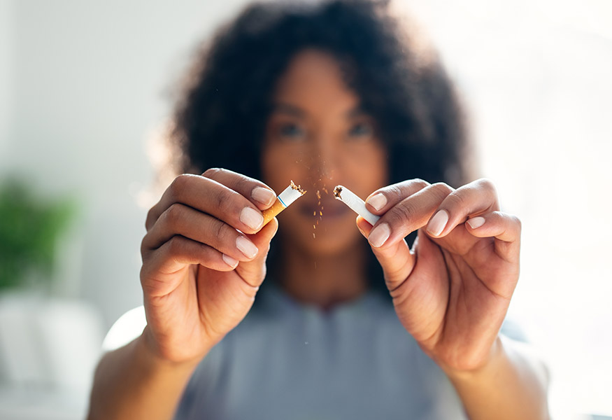 A woman breaking a cigarette in half.
